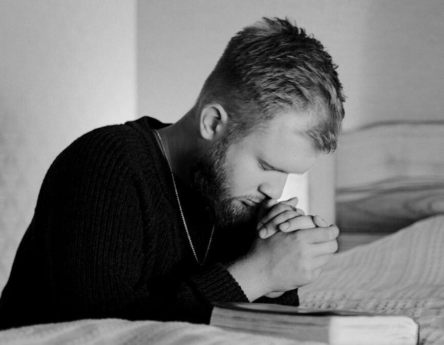 grayscale photo of a man praying