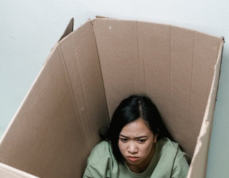 a fearful woman having claustrophobia in a cardboard box