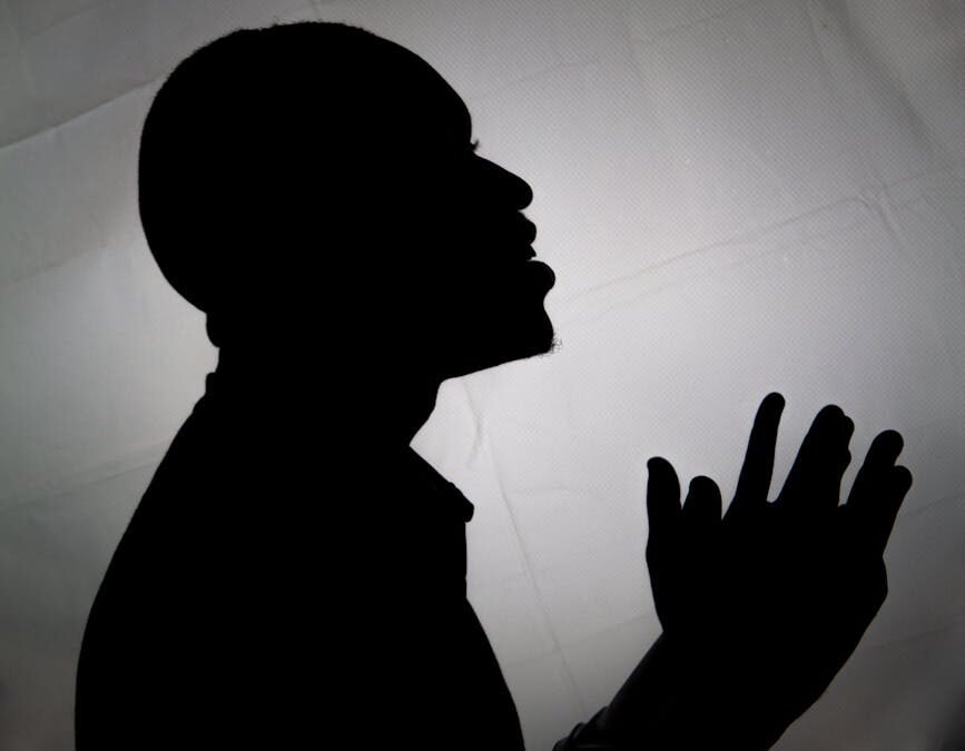 silhouette of person praying against backlight