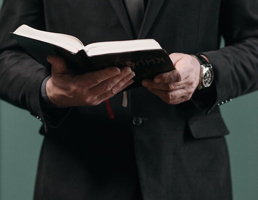 a man in black suit holding an open book