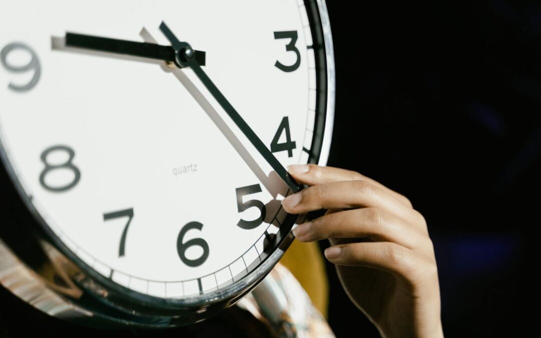 person holding white analog clock