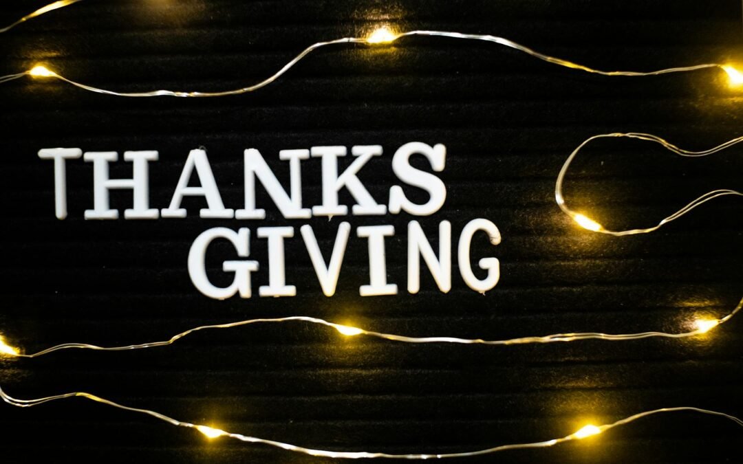 a thanks giving text on a letter board surrounded by string of lights