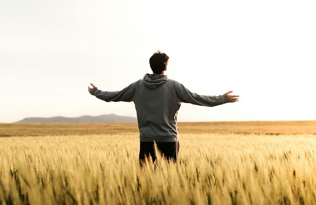 man in gray hoodie standing in middle of field