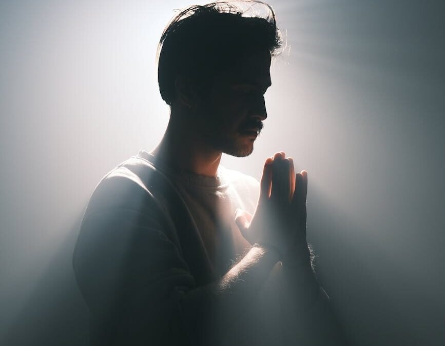 silhouette of a man in meditative pose with dramatic lighting
