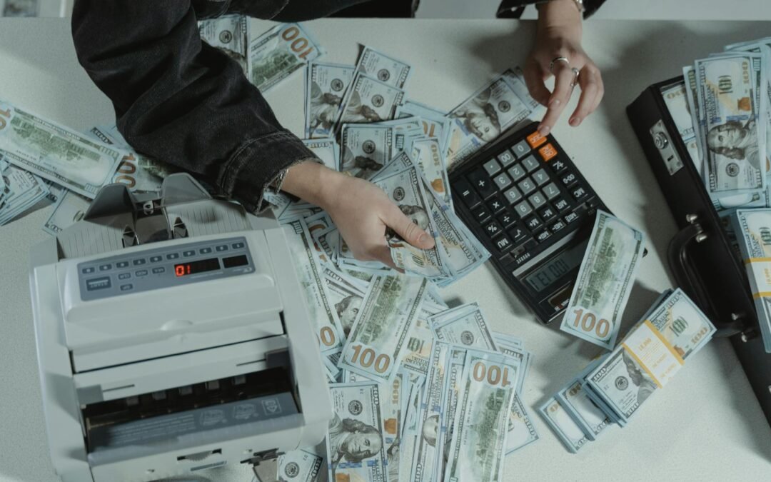 person holding dollar bills while using a calculator