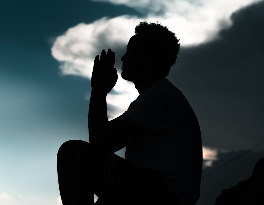 silhouette of a man sitting on rock