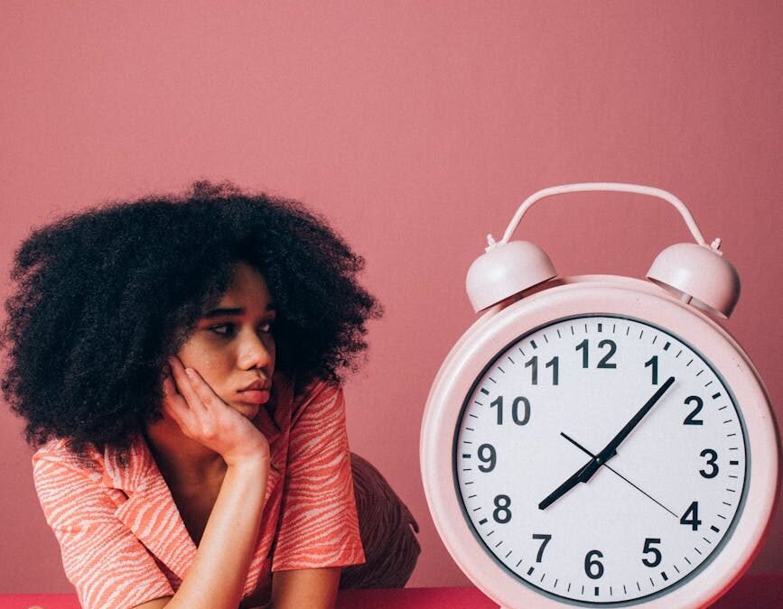 woman looking at a big pink alarm clock