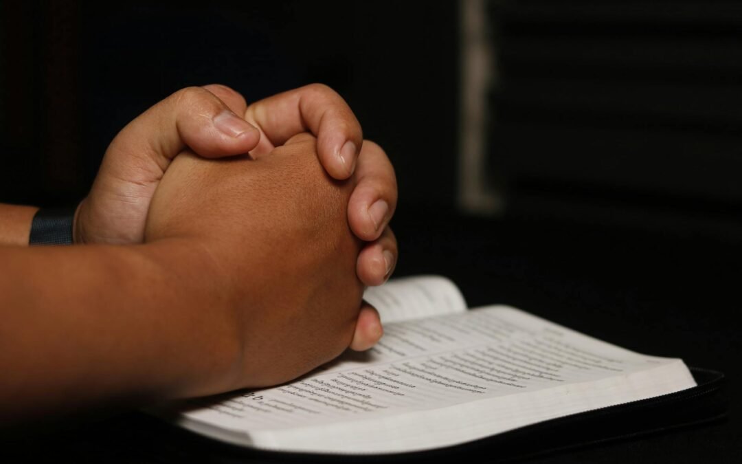 clasped hands on open book