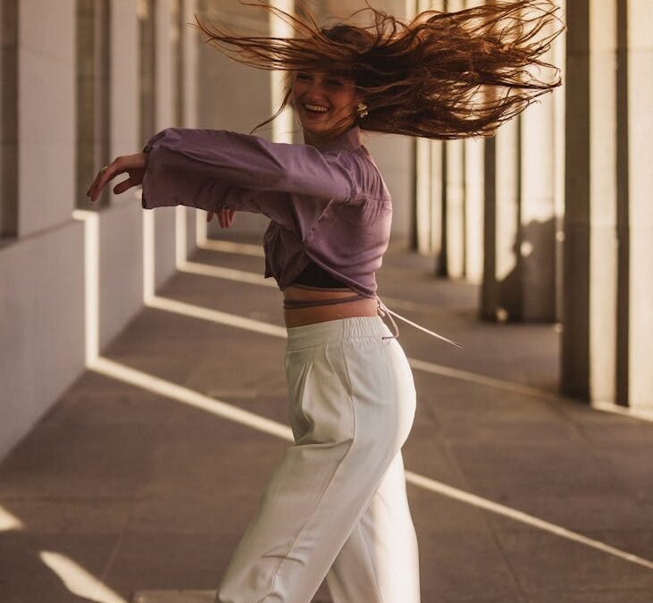 woman dancing joyfully in sunlit corridor