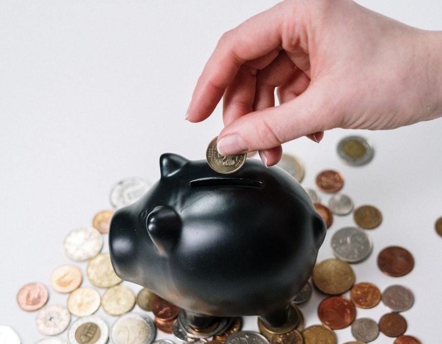 person putting coin in a piggy bank