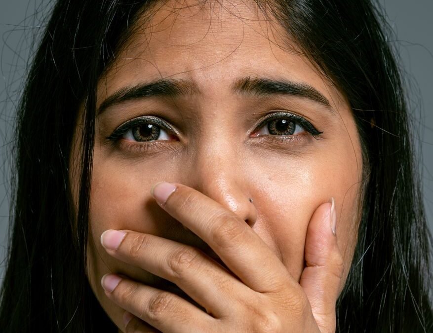 close up portrait of terrified woman covering mouth with hand