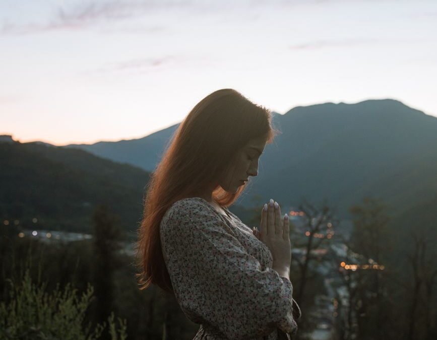 woman standing while praying outdoors