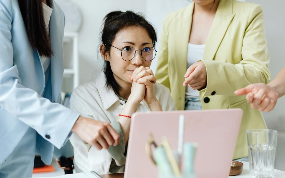 office worker sitting at a laptop with her colleagues pointing on the monitor