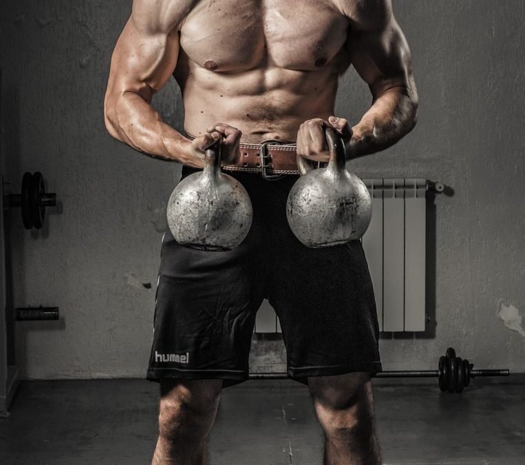 man in black shorts holding black kettle bell