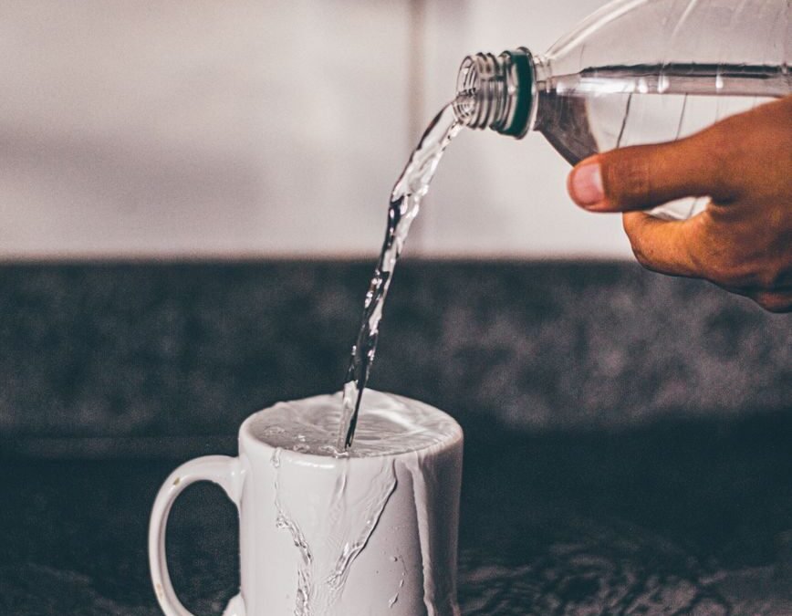 person pouring water on white ceramic mug