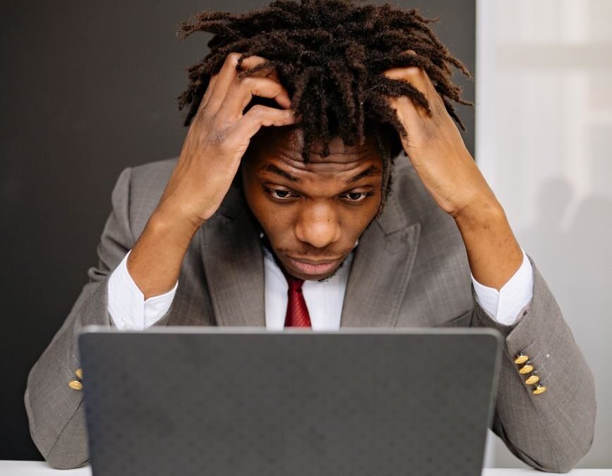 an exhausted man working in front of his laptop