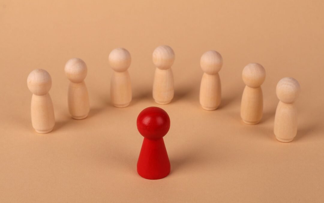 red leader figurine surrounded by wooden figures