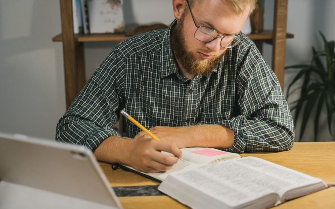 a man reading bible and writing on notebook
