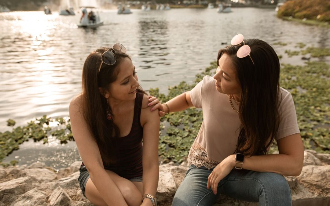 women sitting and talking by a lake